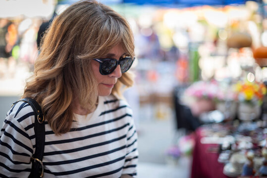 Blond haired mature woman walking at the flea market in an european city