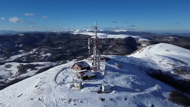 Drone View of Telecommunications Tower on Snow Covered Mountain Peak During Winter