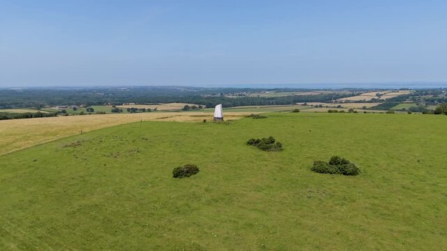 Ashey Down sea mark drone push-in on Isle of Wight, UK. Forward approach from hundreds of metres, camera locked on the beacon and tilting down over patchwork fields.