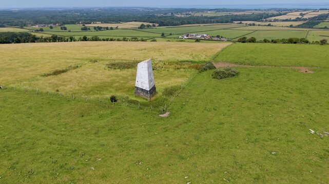 Ashey Down Sea Mark obelisk seen on a slow right ascending drone orbit above open farmland, a historic maritime navigation seamark on the Isle of Wight, England.