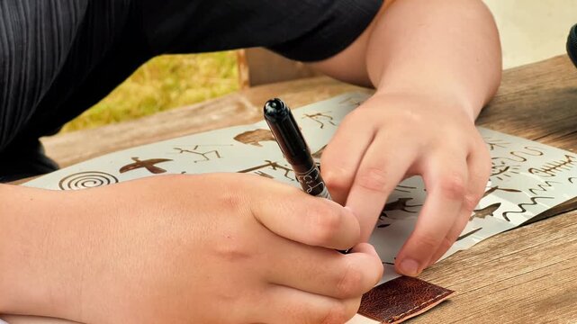 Close-up shot of a person drawing ancient symbols using a plastic stencil and marker. Ideal for educational content, DIY craft tutorials, and hobby marketing campaigns.