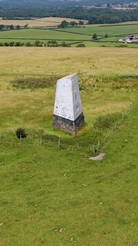 Ashey Down Sea Mark obelisk seen on a slow right ascending drone orbit above open farmland, a historic maritime navigation seamark on the Isle of Wight, England. Vertical format for social media.