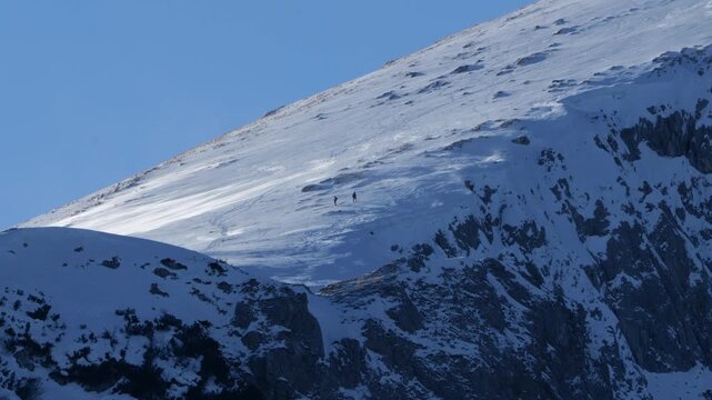 Two Alpinists Descending Snow Covered Mountain During Windy Winter Day, Extreme Alpine Adventure Scene