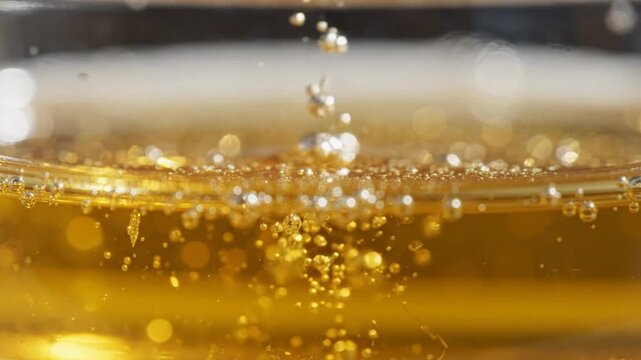 Macro shot of golden skin care serum bubbling in a clean studio with warm bokeh lighting.