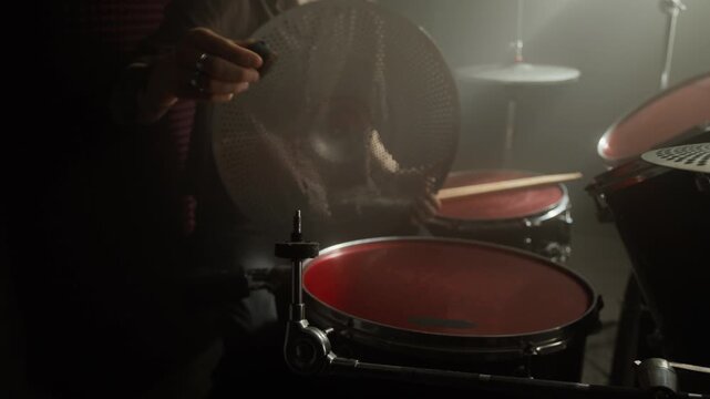 Midsection shot of man setting up drum kit by placing and securing perforated cymbal on stand. Clip for music education promos or musical instrument retail advertisements