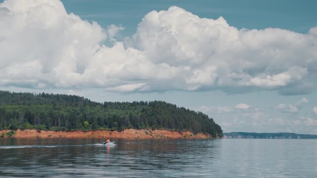 Young man steers inflatable speed boat and moves fast on the calm river