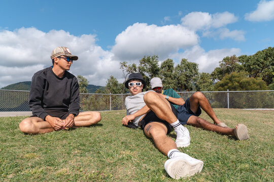 Friends enjoying outdoor leisure in airlie hill, australia, relaxing on grass, building male bonds and friendship