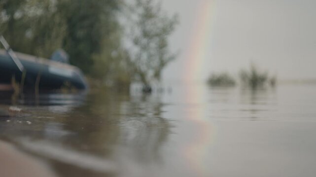 Sandy beach with gentle waves and rainbow in the sky. Coast of the lake after rain