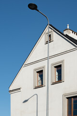 Obraz premium Street light pole casting a shadow on a white residential house facade