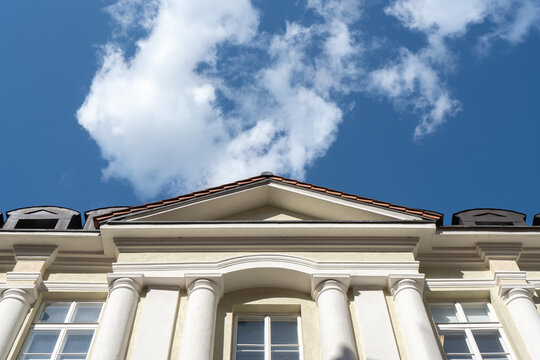 Classical building facade with columns and triangular pediment under sky