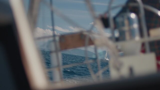 Young man sailor sailing alone the small sailing boat in the fresh sea during nice sunny day. Sailor enjoys the wind. Confident sailor steers the sail boat