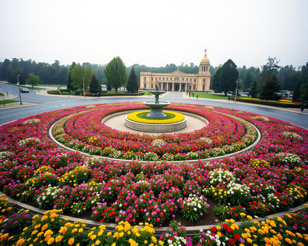 Spectaculaire parterre circulaire avec motifs floraux concentriques en rouge, rose et jaune, jardin ornemental monumental devant un palais baroque europeen, art paysager exceptionnel