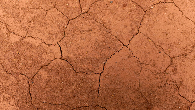 cracked red clay and sandy soil ground surface, creating a natural organic mosaic pattern