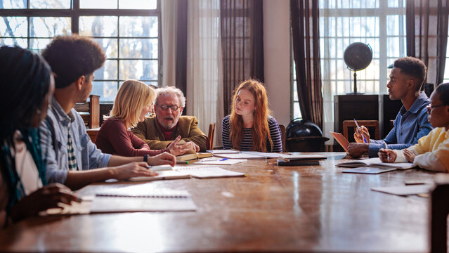 Diverse students collaborating with professor in library seminar