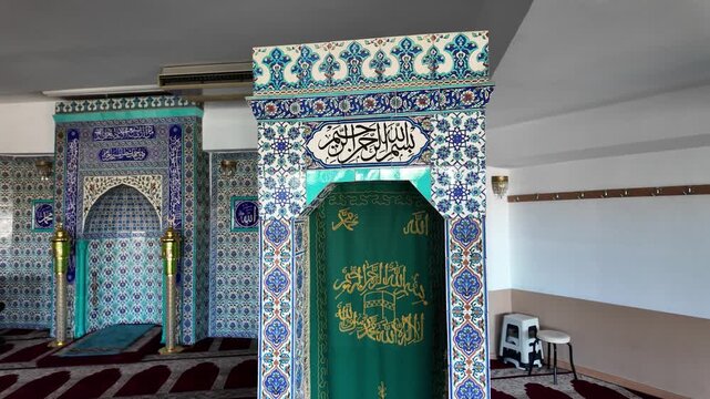 Detailed look at mosque interior showing mihrab and prayer niche decorated with blue Iznik style floral tiles and golden Arabic calligraphy