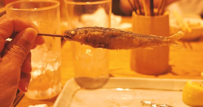 deep-fried skewered fish in hand at the party