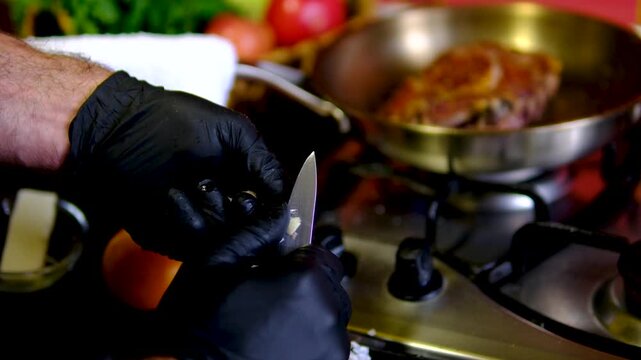 Fresh garlic is carefully prepared before cooking meat as a professional cook removes the peel with a knife. Simple ingredient preparation in a modern restaurant kitchen.