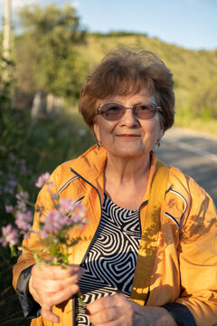 Elderly woman portrait with a bouquet of field flowers outdoor