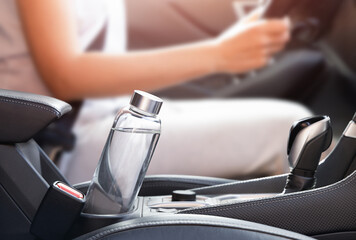 A glass water bottle with a driver in the background. Reusable and Less Plastic concept. © Ирина Гутыряк
