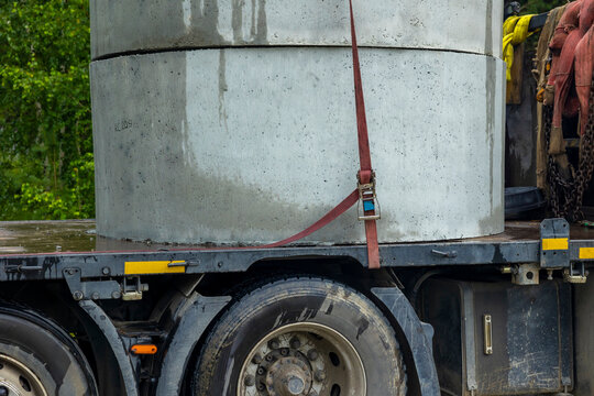 Concrete rings secured on flatbed truck outdoors. Concept: cargo securing