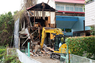 bulldozer demolishing an old abandoned building at a construction site in Japan. Heavy machinery breaking concrete structures with dust, debris and rubble during urban redevelopment. Realistic view of © Андрий Мищак