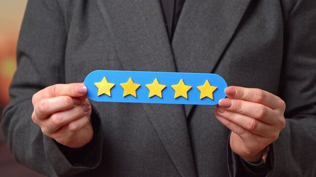 A 5 star plaque in a woman's hand. Popularity and customer satisfaction in business, services, and online platforms. Concept for e-commerce, marketing, feedback, brand reputation, tourism