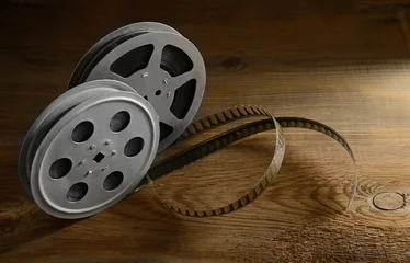 Vintage Metal Movie Reels With Unrolled Film Strip On Old Textured Wooden Table Surface Close Up © Serghei V