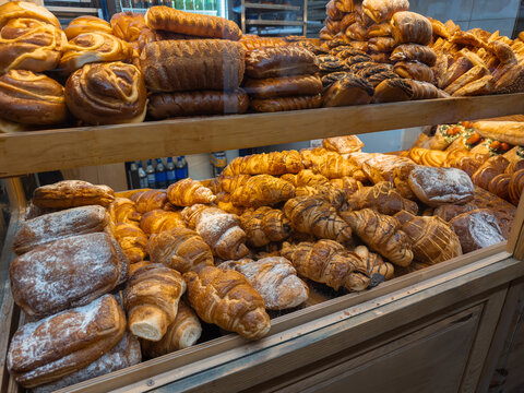Assorted fresh pastries and bread loaves arranged on shelves in a bakery display case, conveying a warm artisan atmosphere and appetizing variety for breakfast or dessert service