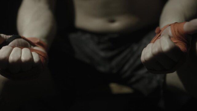 Shirtless boxer with wrapped fists in dramatic low key light