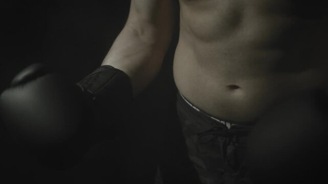 Shirtless boxer holding glove in dramatic low key light
