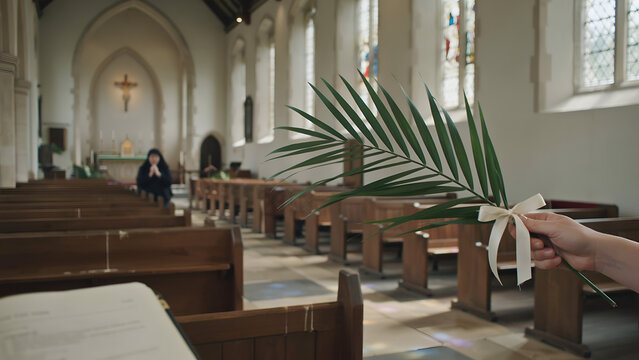Palm frond with bow offered in church during religious service with blurred figure praying