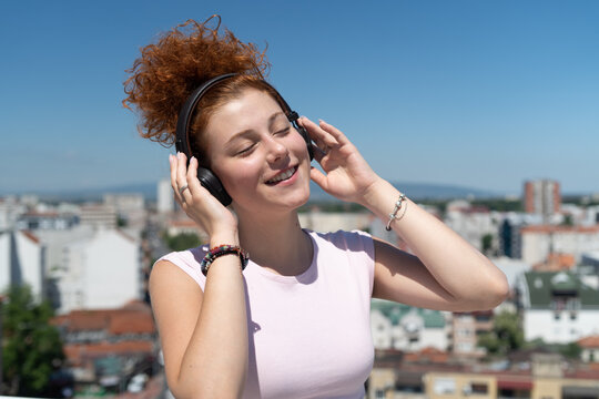 Young woman listening to music on headphones on a building rooftop