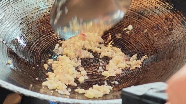 Saut&eacute;ing minced garlic and shallots in a traditional wok close up.