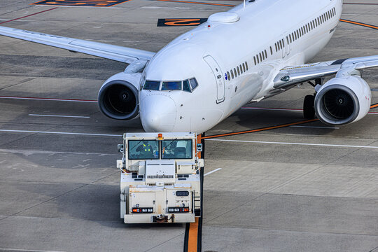 出発準備を整えトーイングカーと連結する白い旅客機