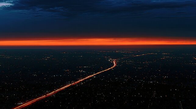 Aerial view of a highway illuminated by car lights at dusk, under a dark sky