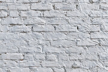 Fototapeta premium Textured white painted brick wall surface with visible brush strokes and imperfections, providing a rustic background.