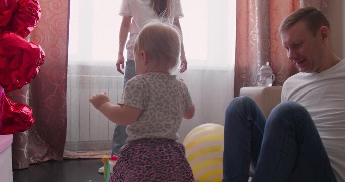 Small child learning to walk with family nearby. Parenting support and early mobility development indoors