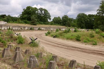 A wide view of a military training ground with sandy roads and defensive obstacles. The outdoor area recreates historical battlefield conditions at a military museum. © Fullip