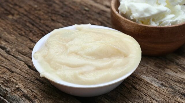 Close-up of pure homemade Indian ghee (clarified butter) in a rustic bowl with a wooden spoon on a vintage wooden table. healthy eating, organic dairy, and Ayurvedic wellness.