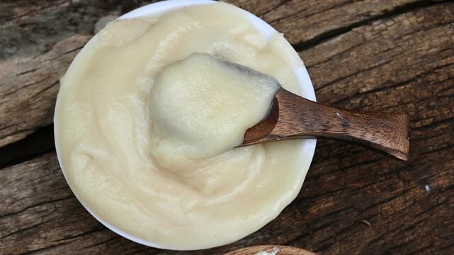 Close-up of pure homemade Indian ghee (clarified butter) in a rustic bowl with a wooden spoon on a vintage wooden table. healthy eating, organic dairy, and Ayurvedic wellness.