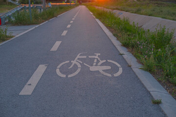 Fototapeta premium Bicycle on a quiet road, lane marking visible under sunset light, urban outdoor scene highlighting cycling, road safety and calm travel