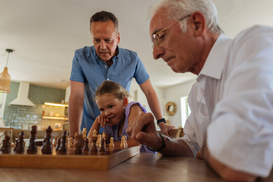 Family members learning chess on a wooden table