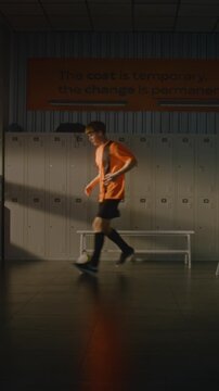 Teenage Footballer Alone in Gym Locker Room, Practicing Freestyle Ball Tricks and Control. Player, Dressed in Team Uniform, Absorbed in Routine. Pre Game Preparation of Youth Sports. Vertical Shot.