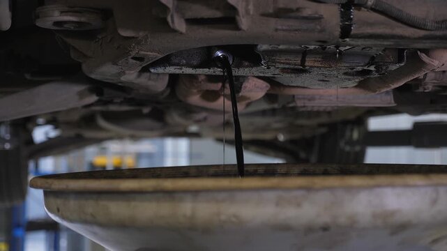 A detailed view of the car draining excess engine lubricant to ensure the required pressure during the engine oil change at the service station.