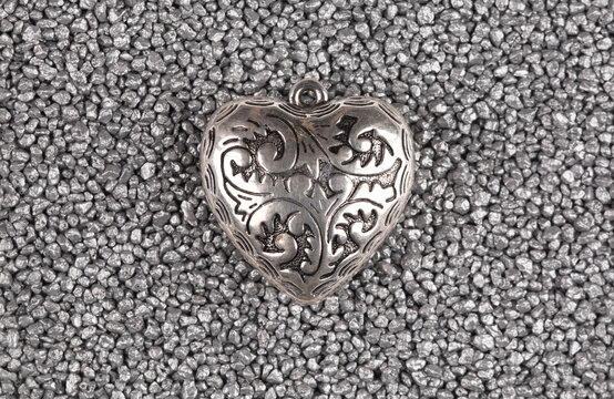 Silver heart pendant isolated on silver sand