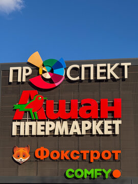 Kyiv, Ukraine - March 16, 2026: Prospekt shopping center facade with Auchan, Foxtrot, and Comfy store signs against a clear blue sky, showing modern retail architecture design