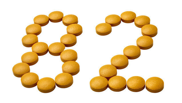 Isolated bright yellow round pills forming the number eighty-two, medical health and dosage concept
