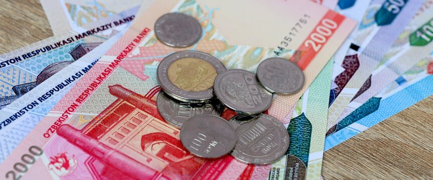 Uzbekistani som money bills and coins on table. Uzbekistan cash of UZS currency close up