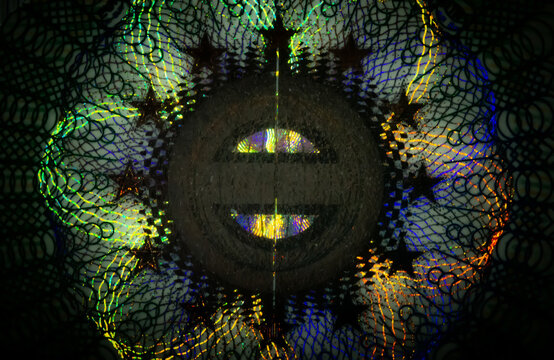 A close-up of the illuminated holographic emblem of the EU Schengen visa. The iridescent multicolor security hologram of the Schengen visa of the European Union countries. Macro photography.