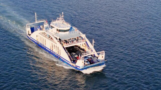 Car ferry transporting vehicles across bay water. Public ferry service connecting road traffic over water